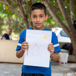 Porträttbild på Louis, 9 år, i Libanon som håller upp en teckning av ett hus som han har ritat.