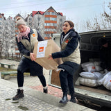 Två hjälparbetare, anställda hos NRC i Moldavien, bär en låda med NRC:s logotyp på från en mindre lastbil. I bilen finns mer vinternödhjälp till människor på flykt, redo att lastas av.