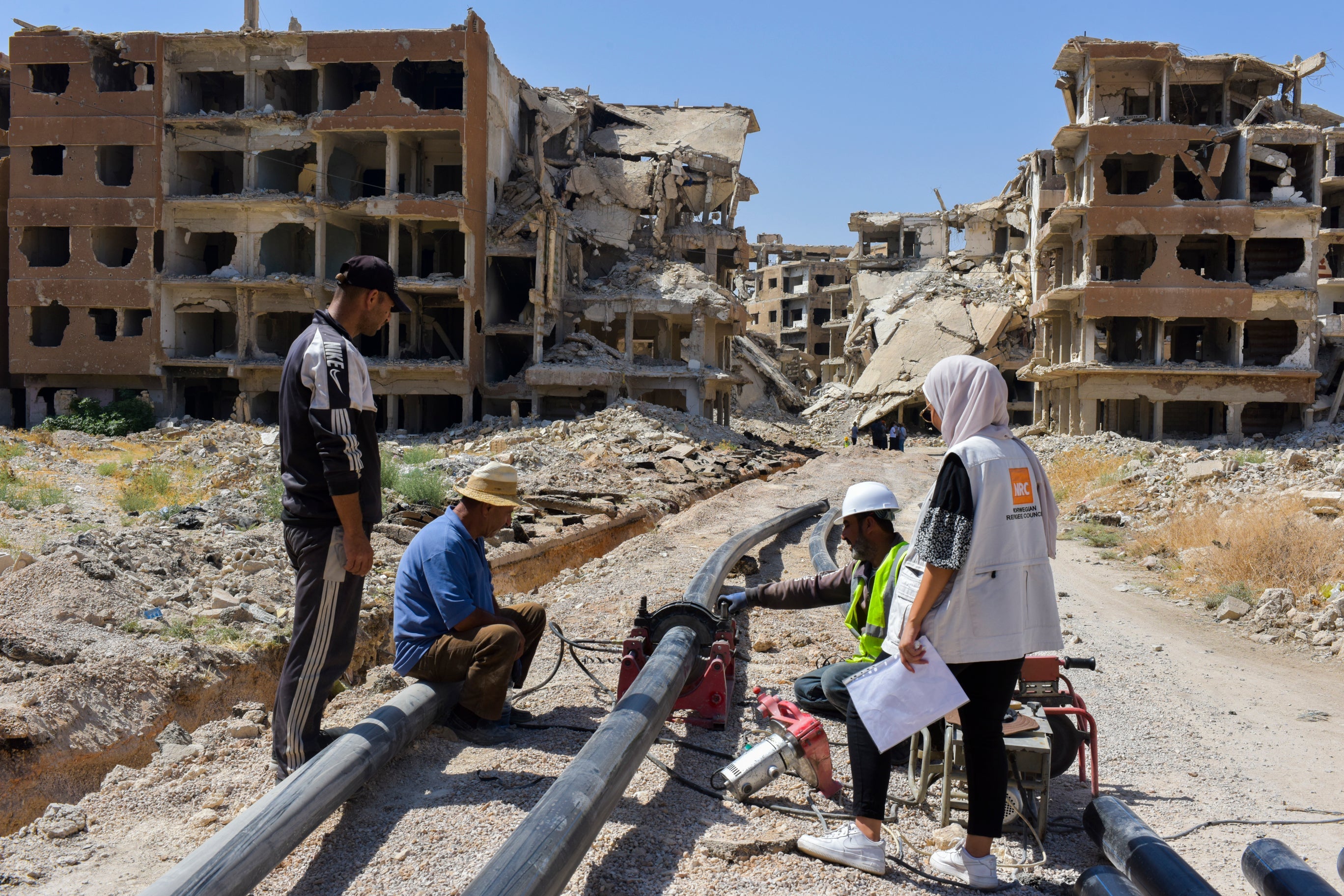 Reparation av vattensystem som skadats efter jordbävningen i Syrien 2023. I bakgrunden syns skadade byggnader.