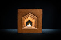 Det färdigbyggda pepparkakshuset ”Hemmet som är borta” sett framifrån, odekorerat och med ett tänt led-ljus placerat i huset.