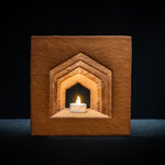 Det färdigbyggda pepparkakshuset ”Hemmet som är borta” sett framifrån, odekorerat och med ett tänt led-ljus placerat i huset.