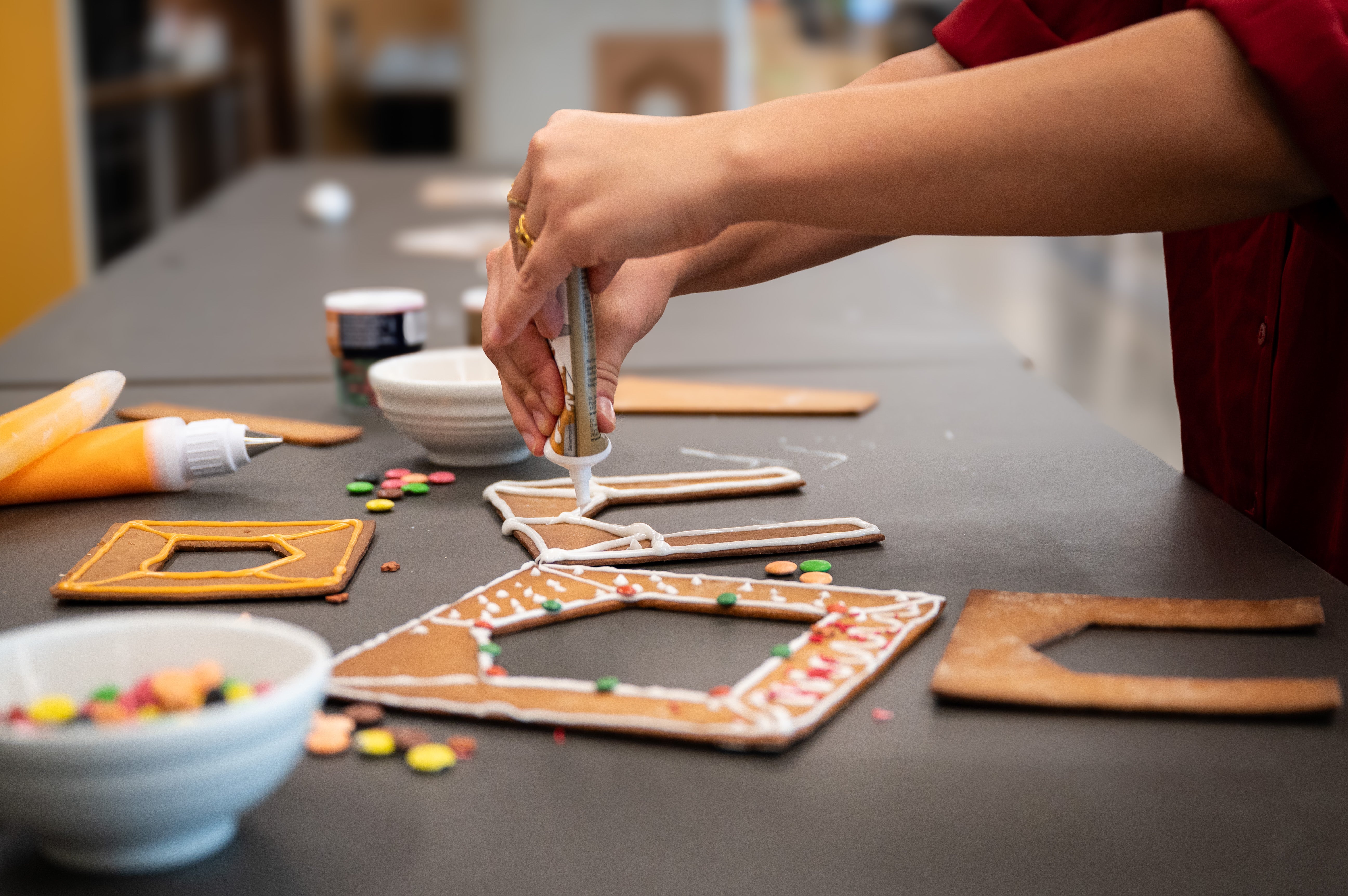En person dekorerar delar av pepparkakshuset ”Hemmet som är borta” med kristyr.